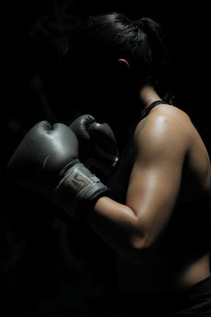 pexels-photo-1608099-1608099 A powerful image of a female boxer showcasing strength and determination in a dark setting.
